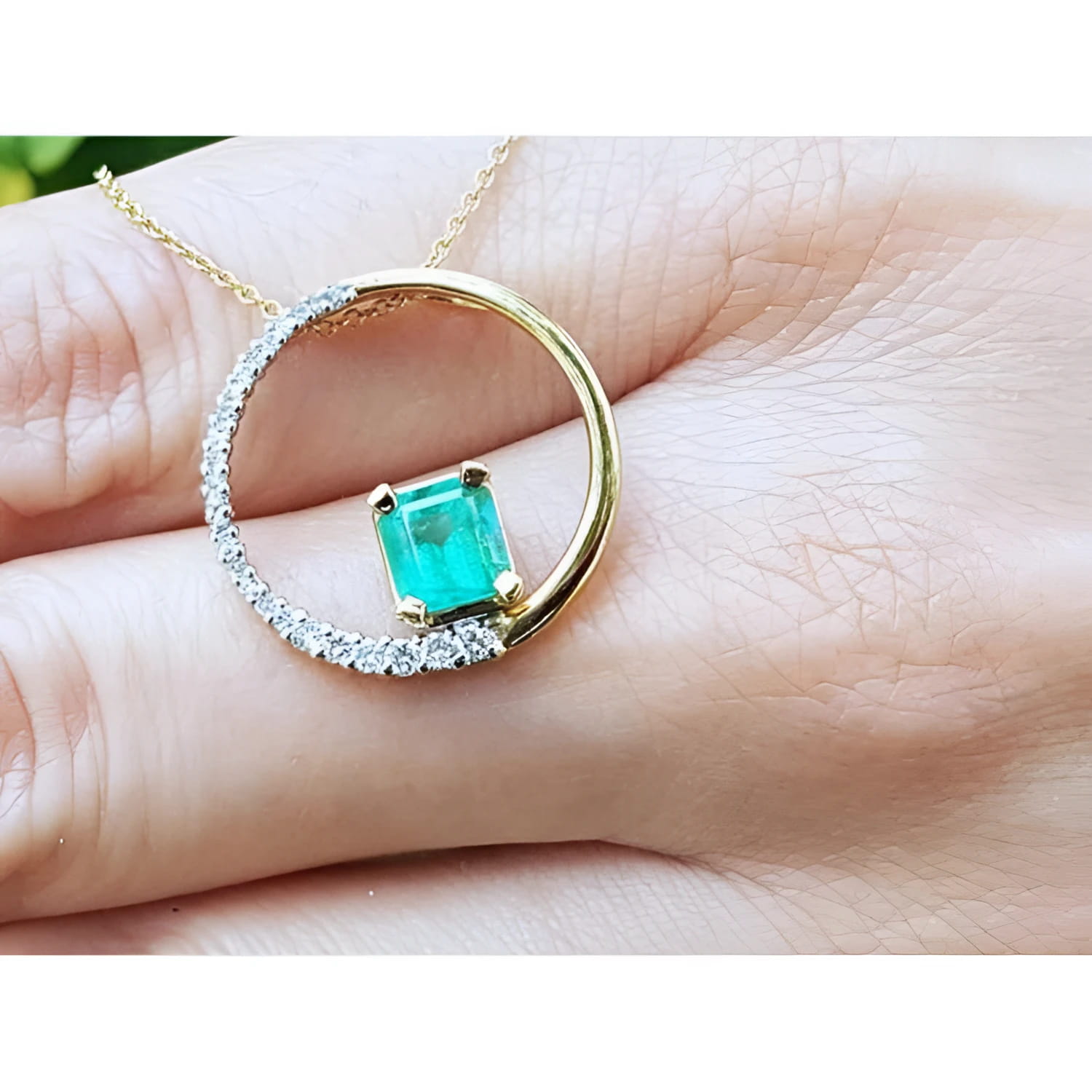 14K gold circle pendant with a 1.08 ct emerald center stone and half pavé natural diamonds.