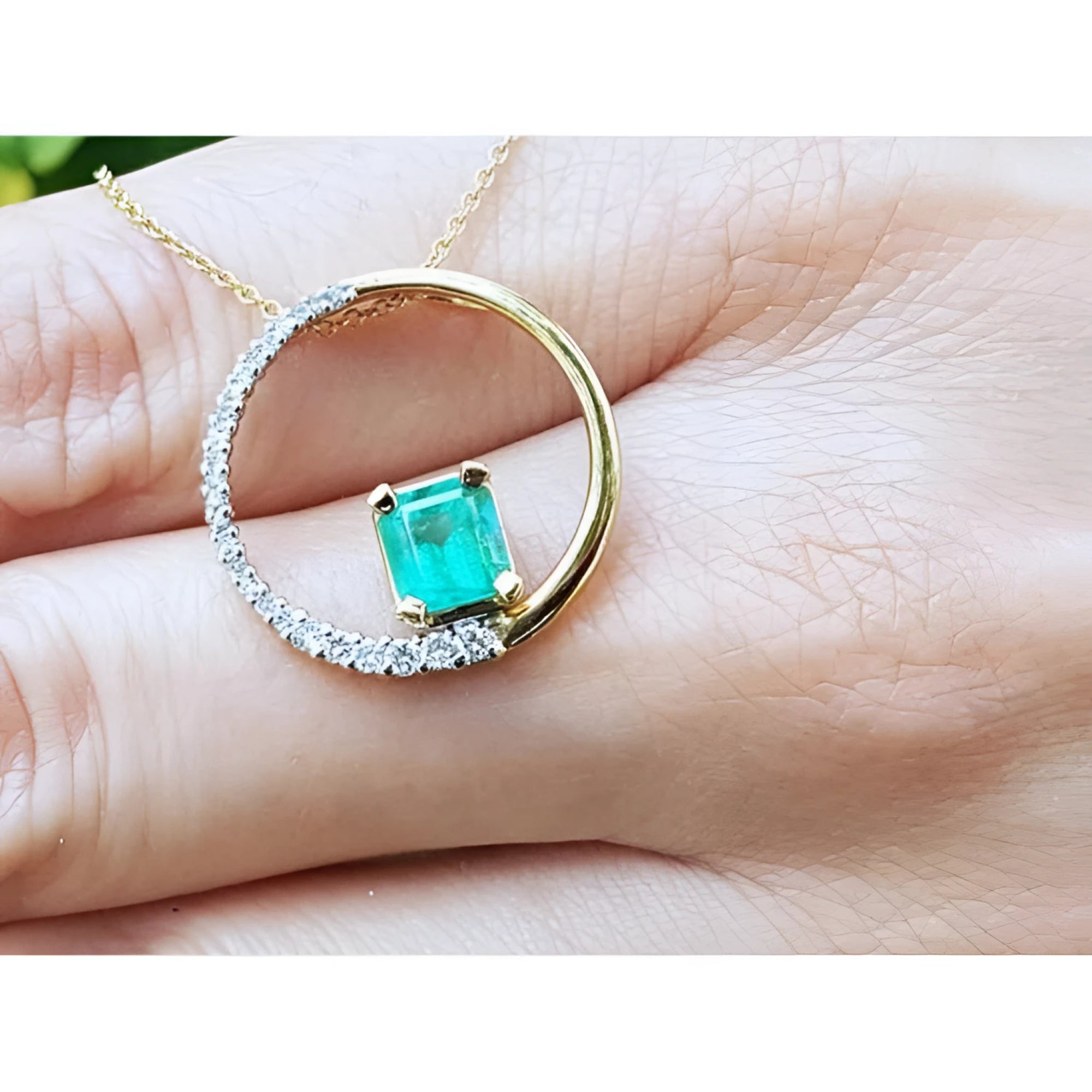 14K gold circle pendant with a 1.08 ct emerald center stone and half pavé natural diamonds.