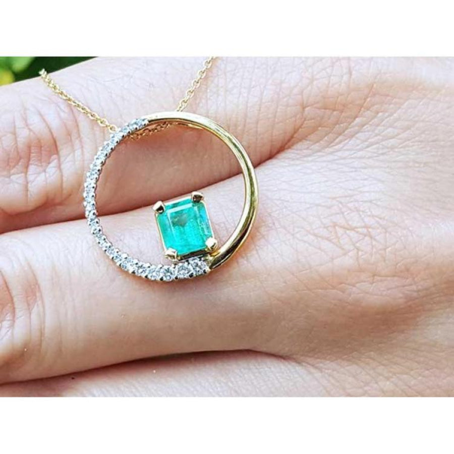 14K gold circle pendant with a 1.08 ct emerald center stone and half pavé natural diamonds.