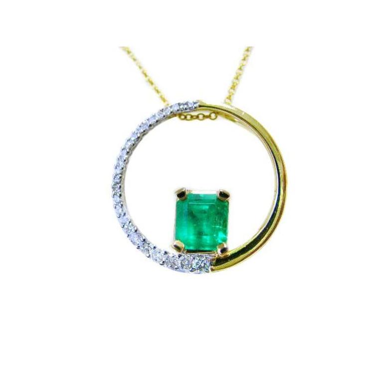 A yellow gold circle of life pendant necklace with a center square natural colombian emerald topside displayed.