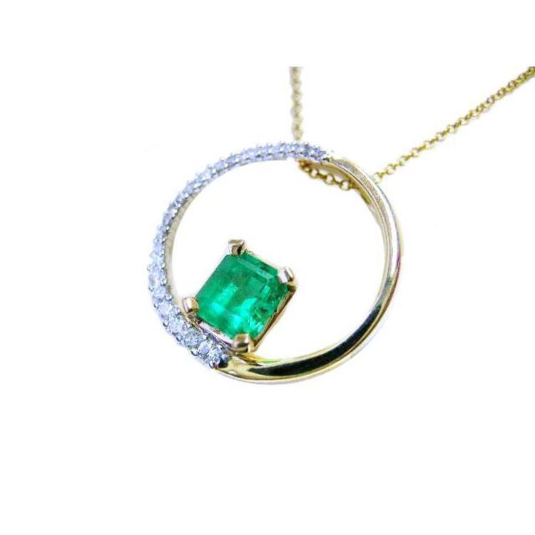 Gold necklace meaning the circle of life with a natural emerald and circular design on a white background.