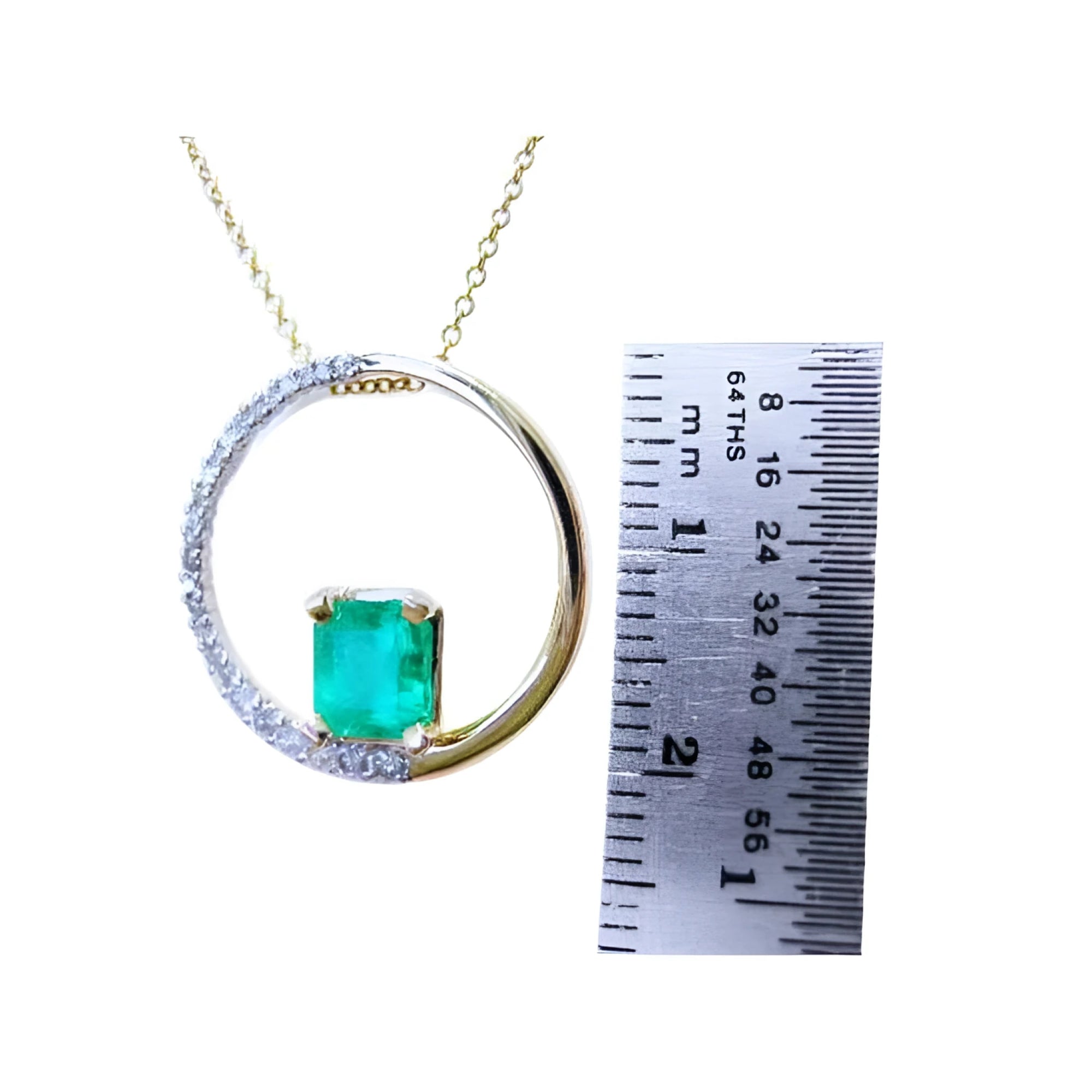 Gold circle of life pendant with a square natural emerald and diamonds, next to a ruler for scale.