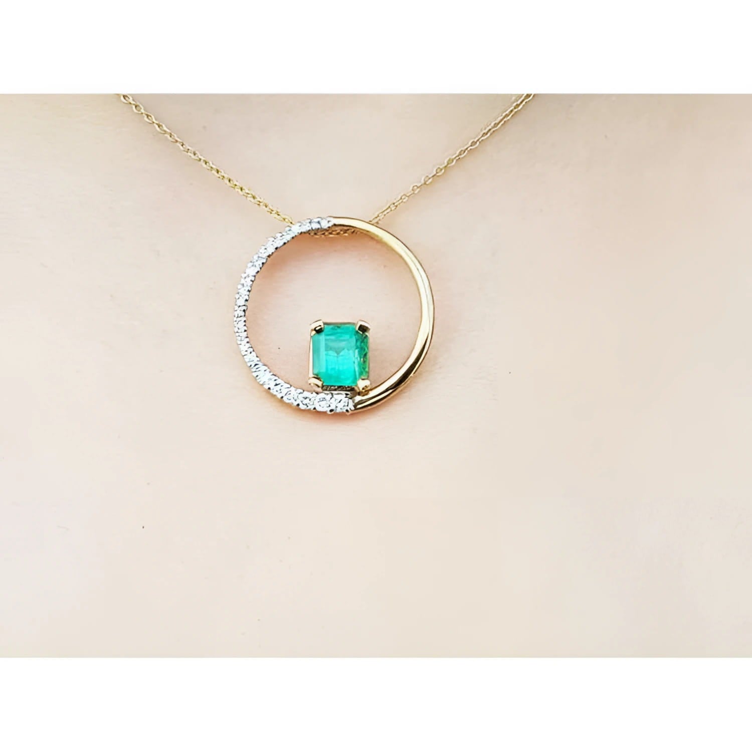 14K gold "Circle of Life" pendant with a rectangular emerald center stone and half pavé diamonds.