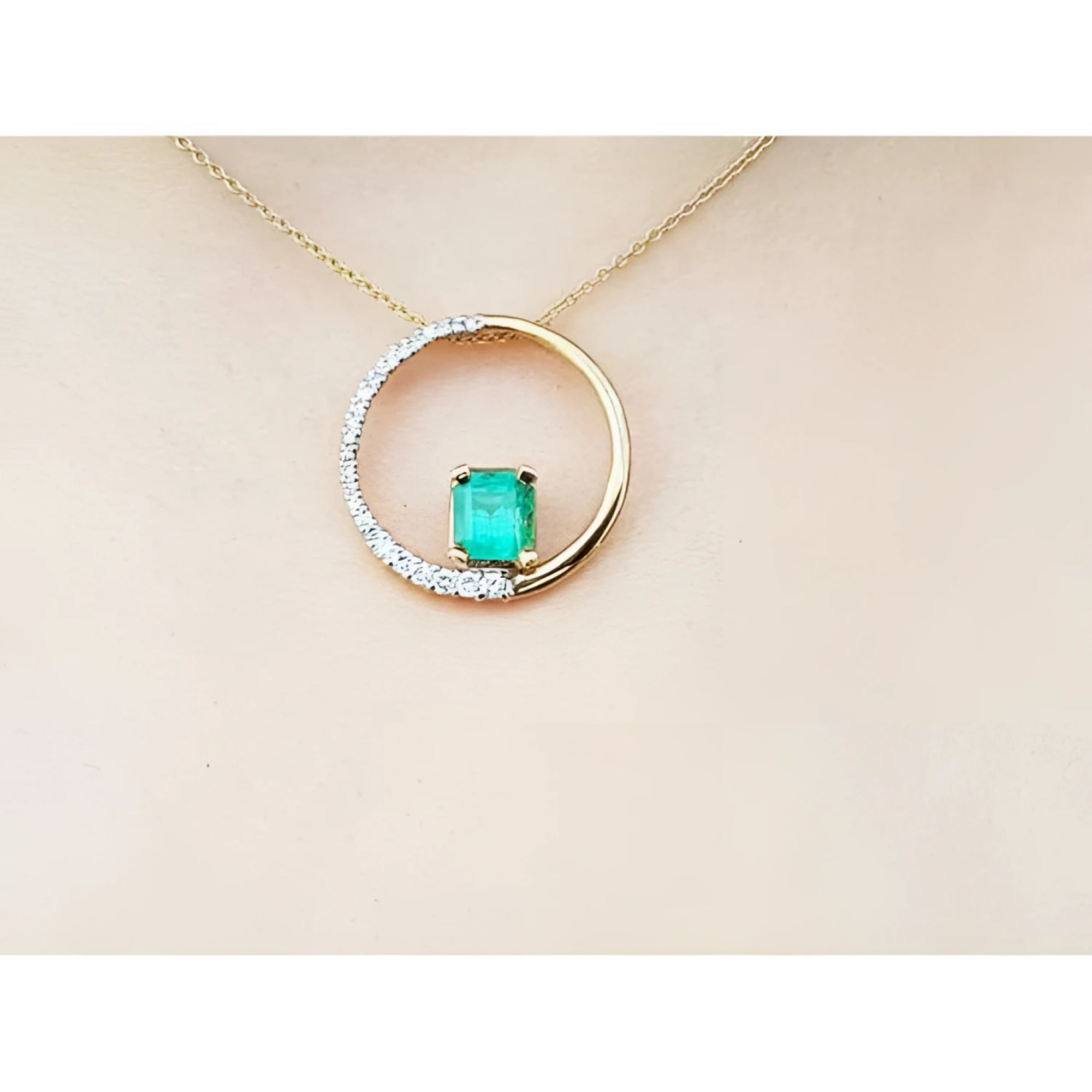 14K gold "Circle of Life" pendant with a rectangular emerald center stone and half pavé diamonds.