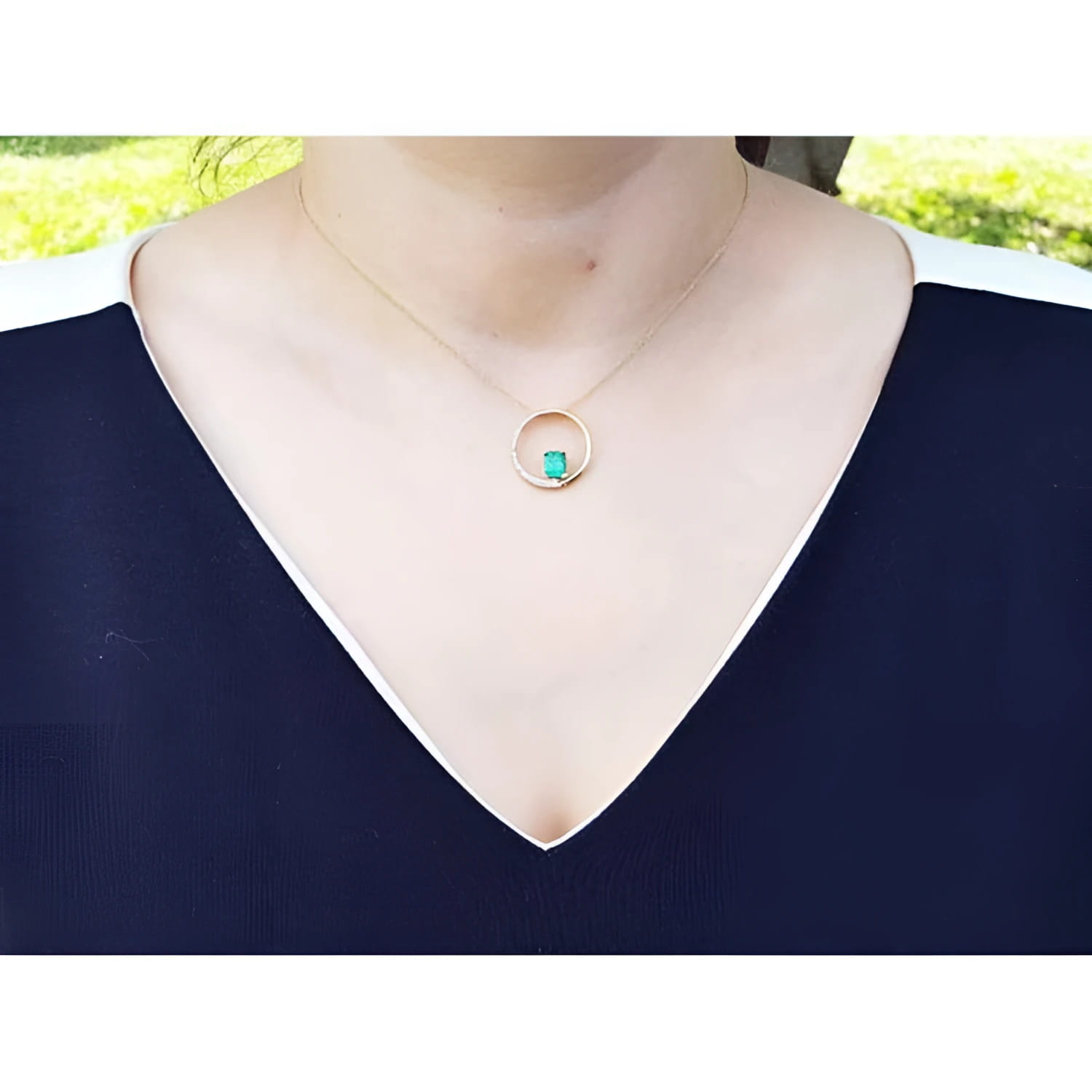 14K gold "Circle of Life" emerald pendant with diamonds, worn on a woman's neck.