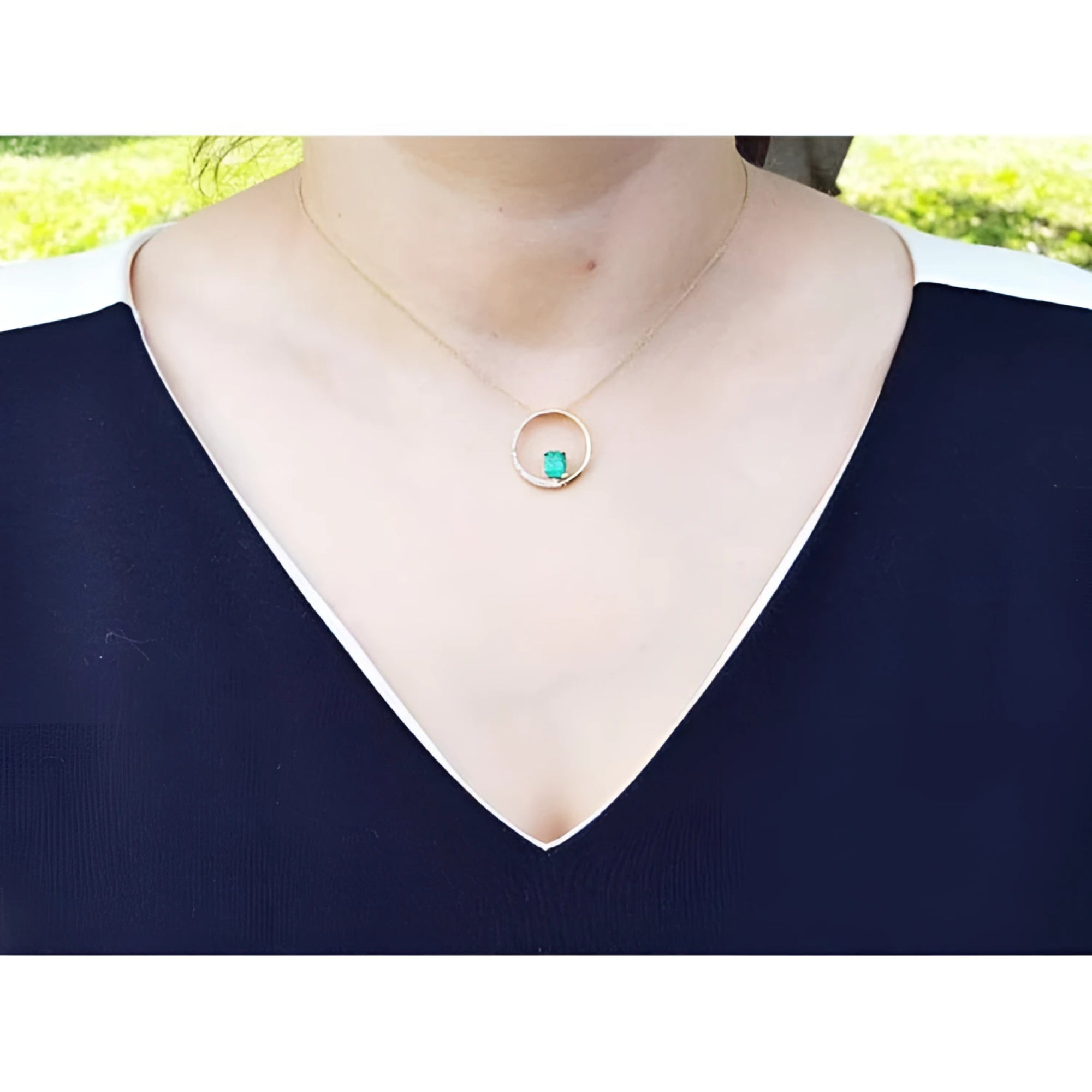 14K gold "Circle of Life" emerald pendant with diamonds, worn on a woman's neck.