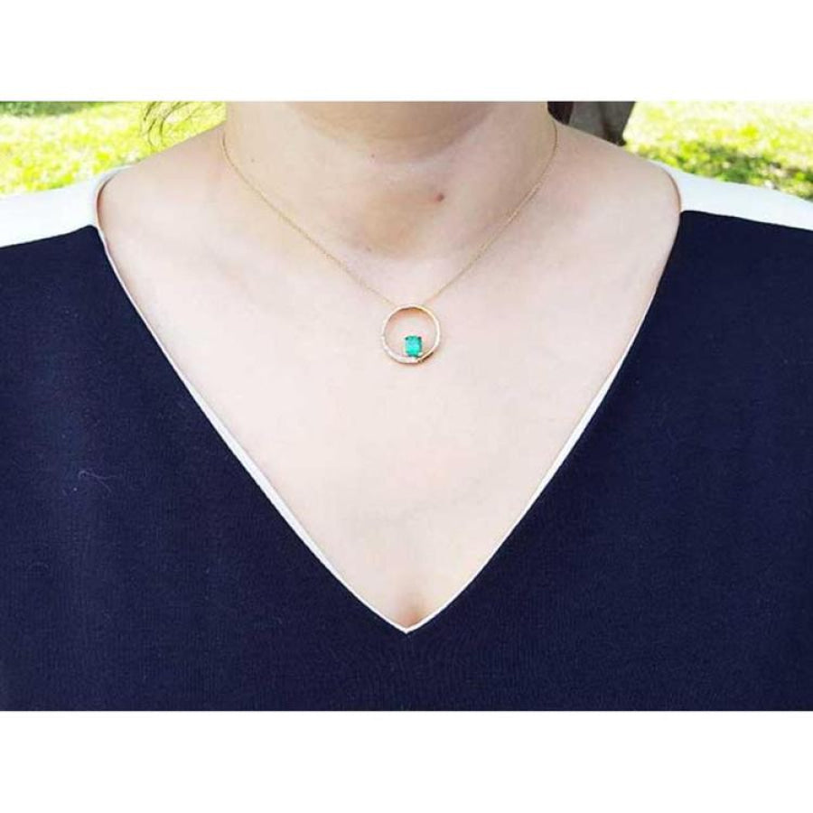 14K gold "Circle of Life" emerald pendant with diamonds, worn on a woman's neck.