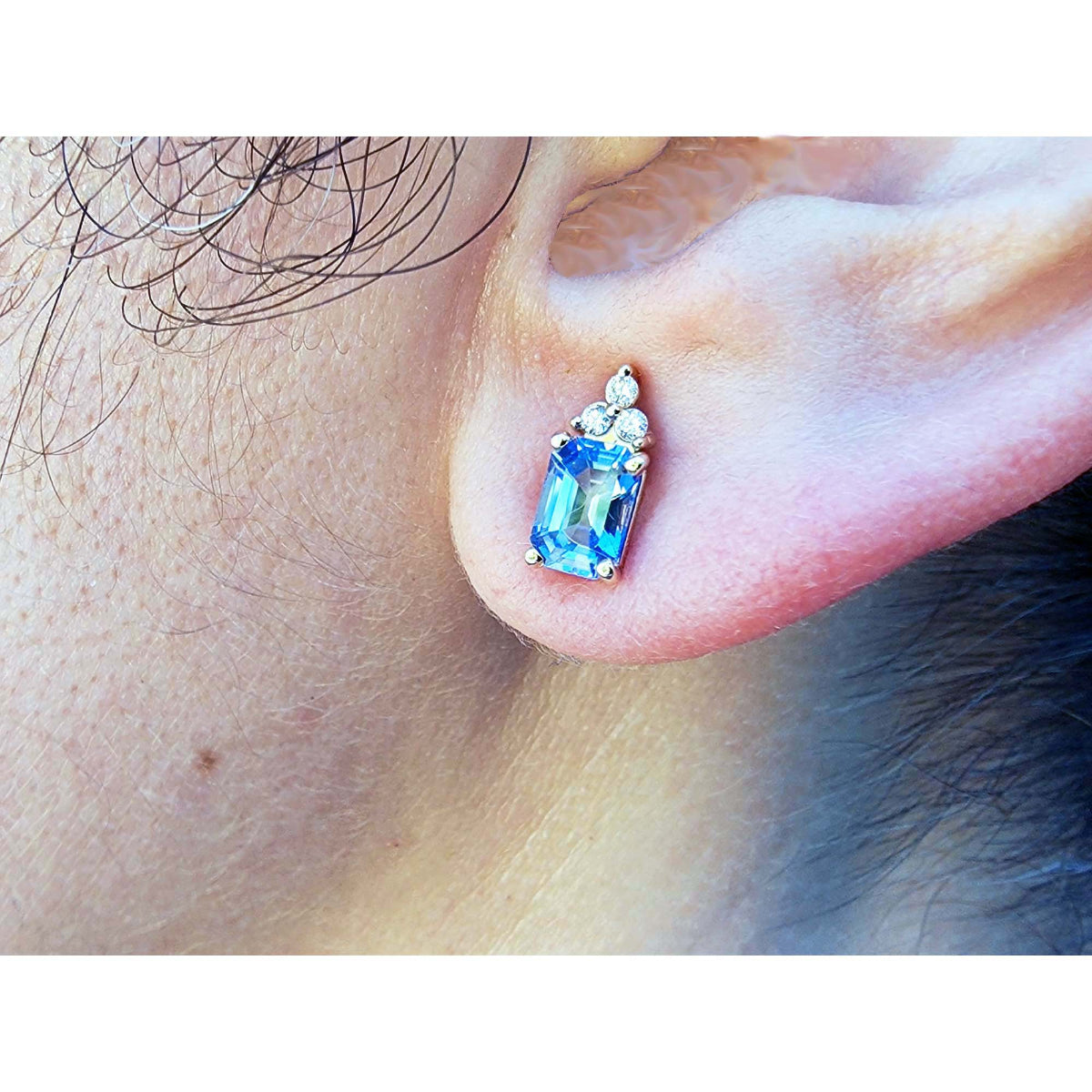 Close-up of an ear wearing a blue sapphire earring.