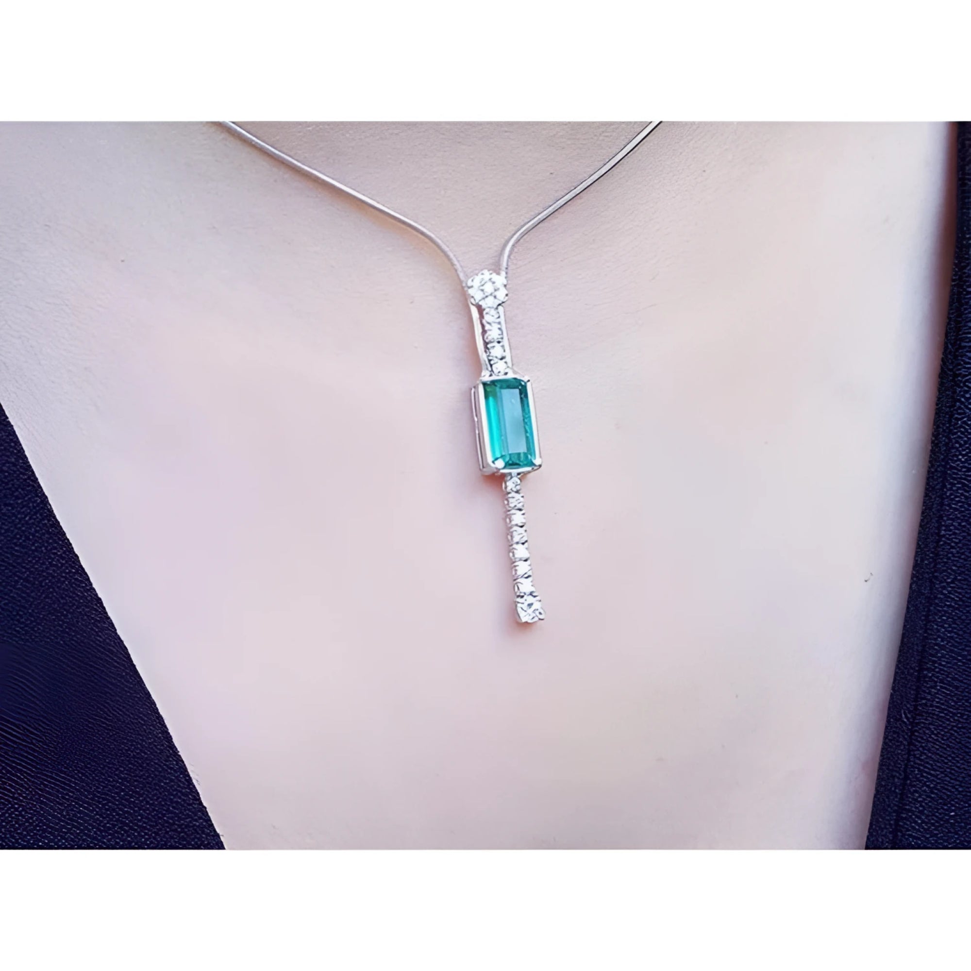 White gold necklace with a rectangular Colombian emerald pendant and diamond accents.