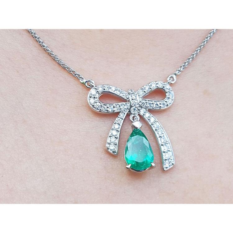 18K white gold bow-tie necklace with a pear-shaped deep green emerald pendant.