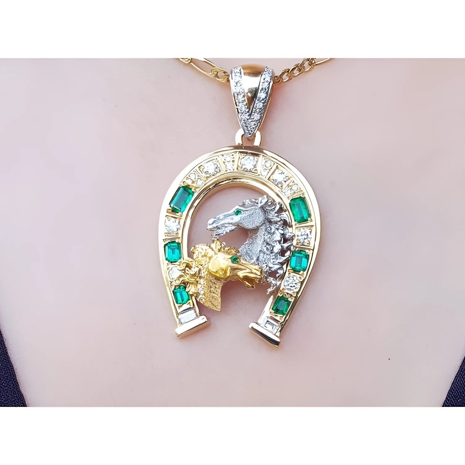 18K yellow gold horseshoe pendant with emeralds, diamonds, and two horse heads.