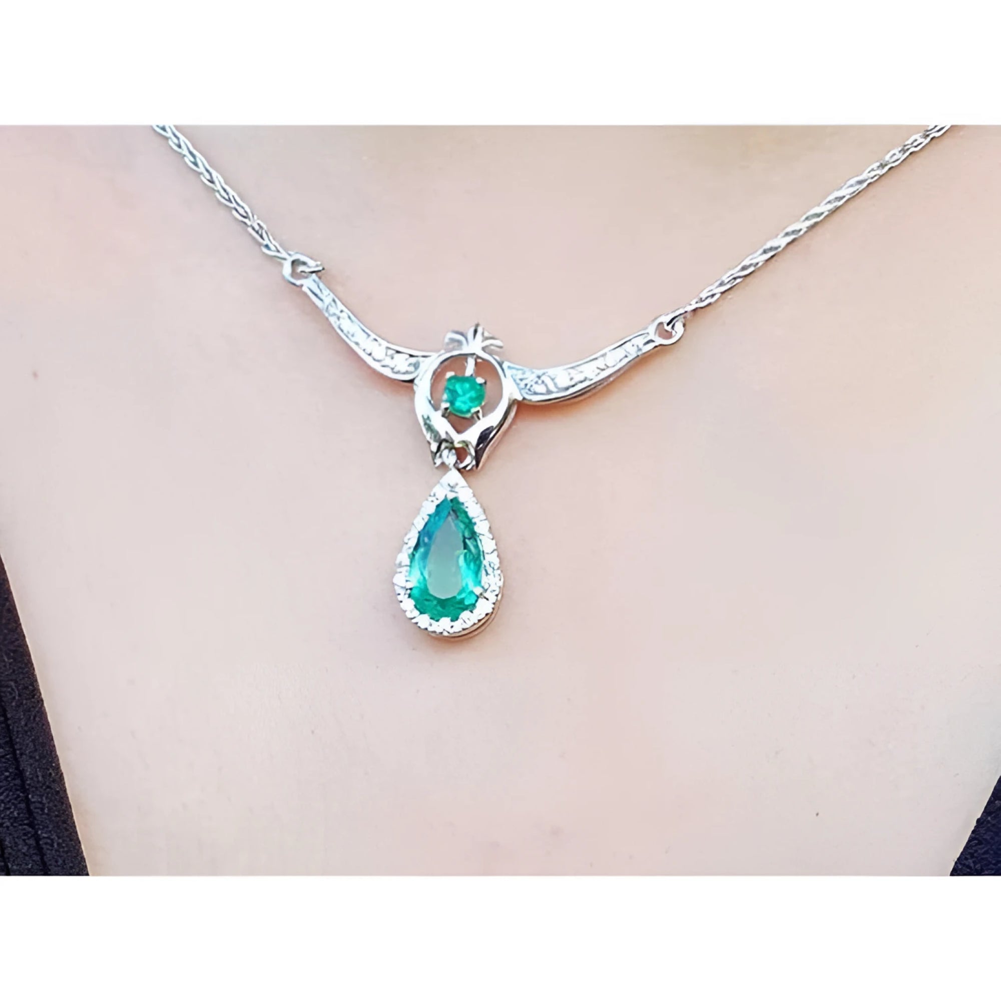 14K white gold necklace with a pear-shaped emerald pendant surrounded by diamonds.