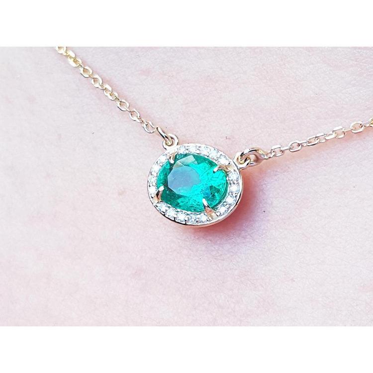 0.90 carat oval Muzo emerald necklace with diamond halo on a 14K yellow gold chain.