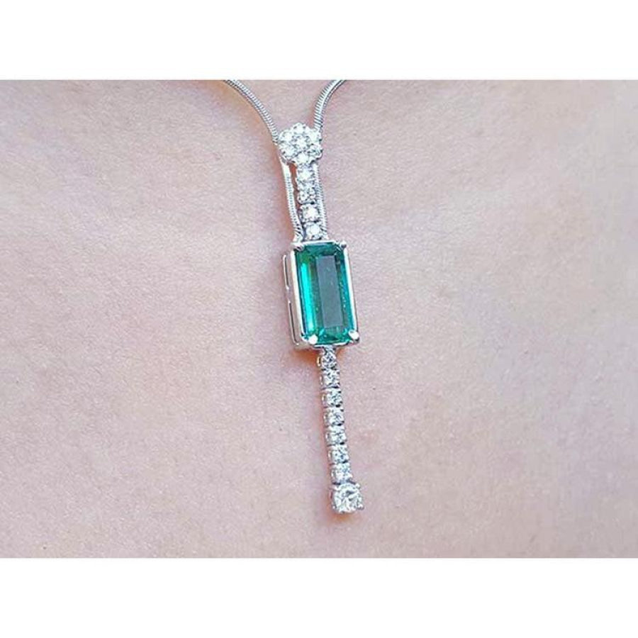 White gold women's necklace with a rectangular Colombian emerald and diamond accents, worn on a neck.
