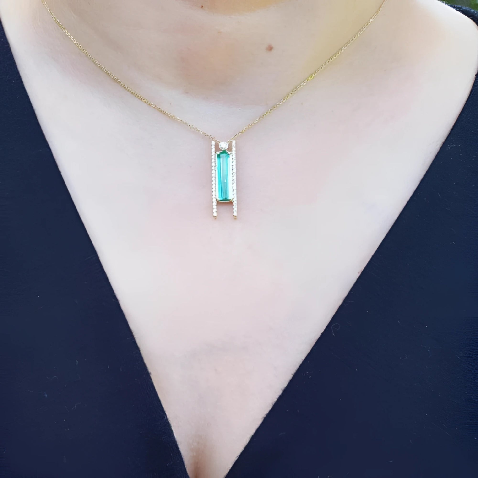 Emerald baguette cut necklace with natural diamonds, 14K yellow gold, worn on a person.