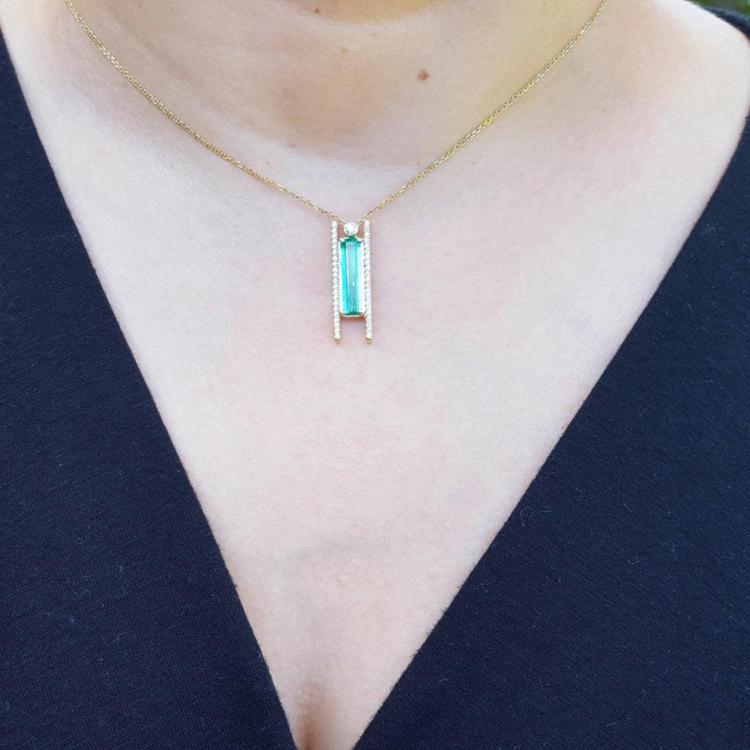 Emerald baguette cut necklace with natural diamonds, 14K yellow gold, worn on a person.