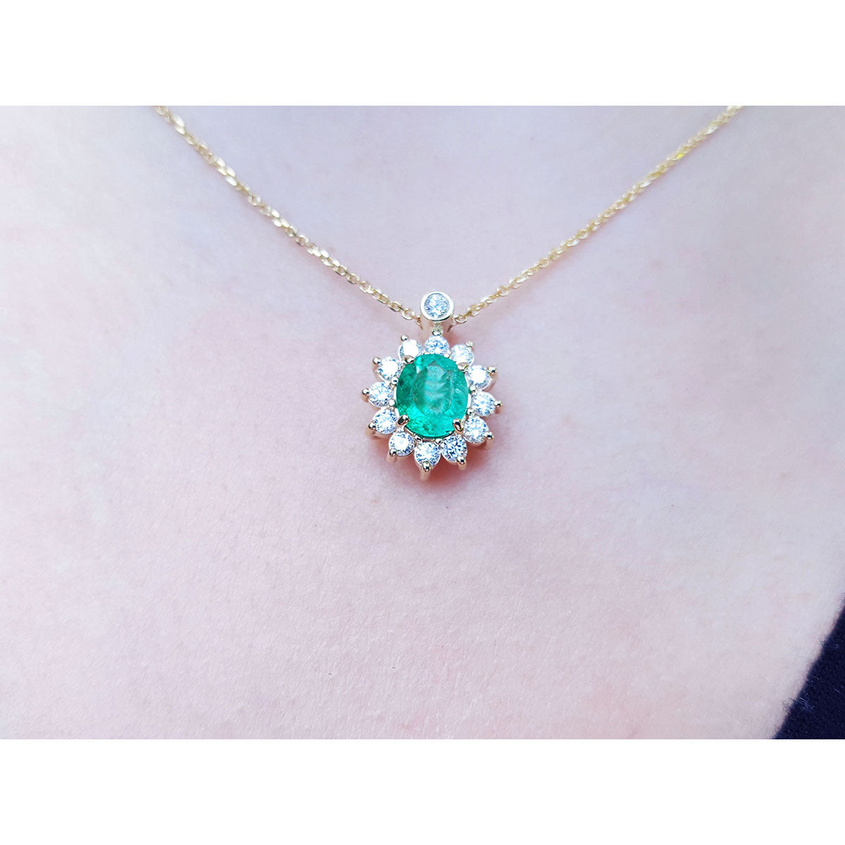 A closer view of a yellow gold necklace with a natural Muzo emerald gemstone pendant on a women&#39;s neck