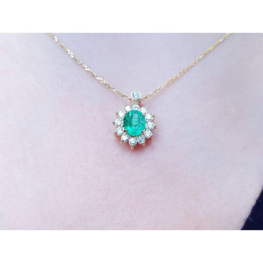 Oval cut 1.11 ct. emerald and natural diamond cluster necklace on a 14K yellow gold chain.