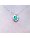 A closer view of a yellow gold necklace with a natural Muzo emerald gemstone pendant on a women's neck