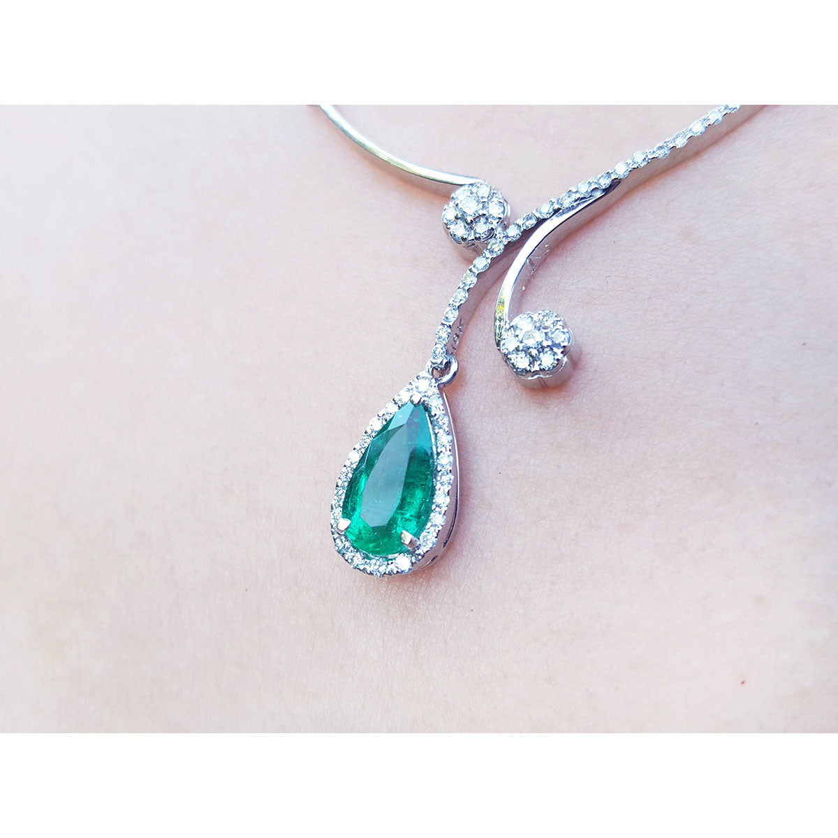 Elegant white gold necklace with a teardrop-shaped emerald pendant into halo diamond on lady&#39;s collar