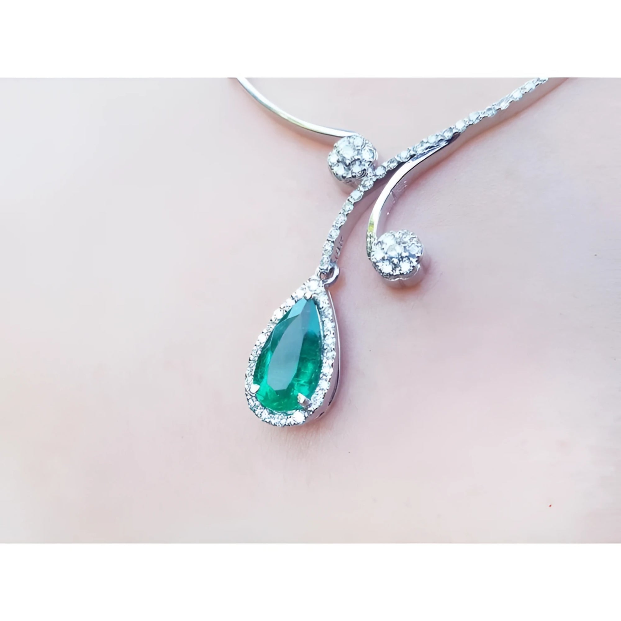 Pear cut 2.26ct natural emerald necklace in 18K white gold with diamond halo and accents.