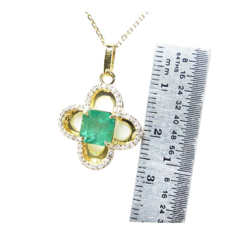 14K gold clover pendant with a square Colombian emerald and diamond accents, shown with a ruler for size.