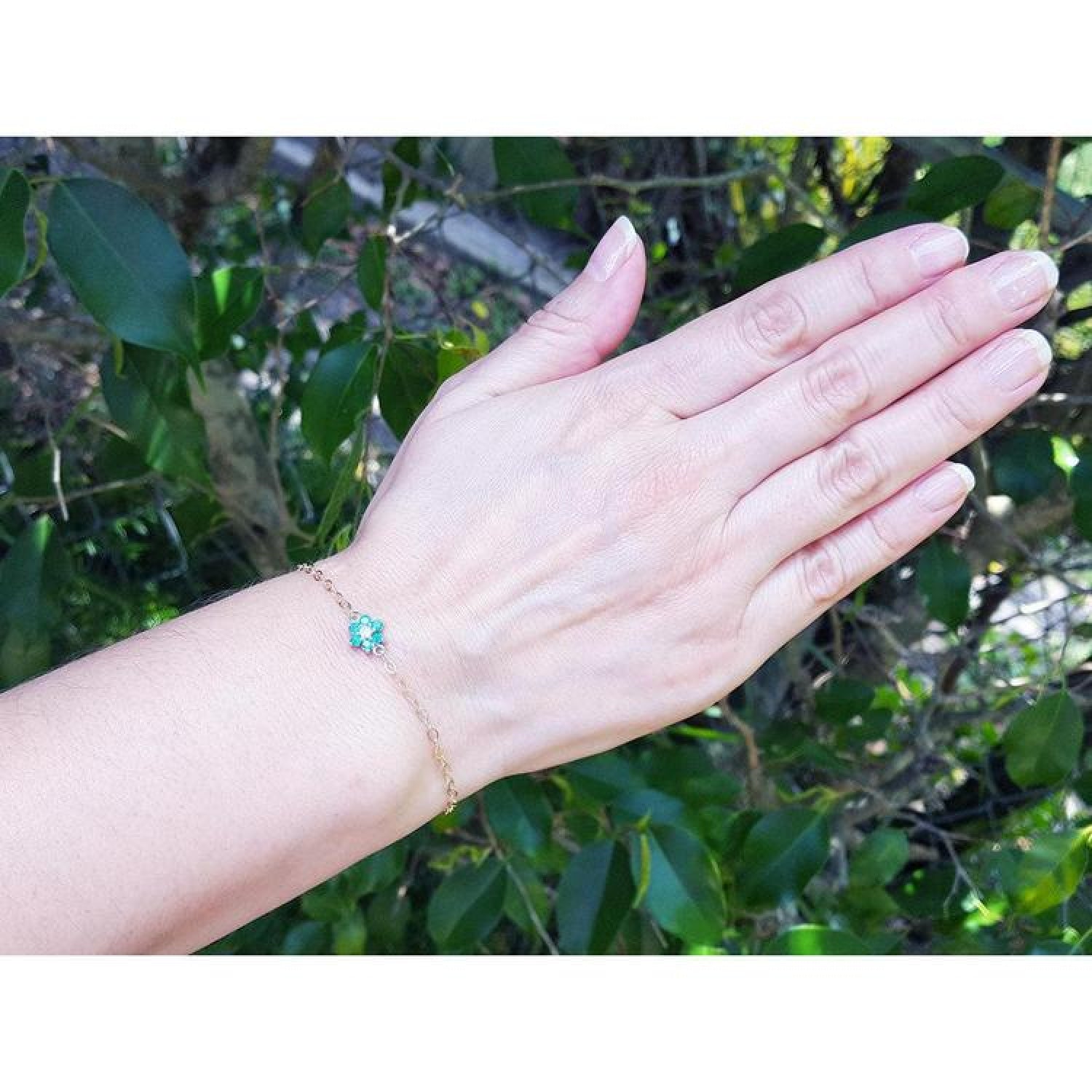 14K yellow gold bracelet with a central emerald and diamond cluster on a woman's wrist.
