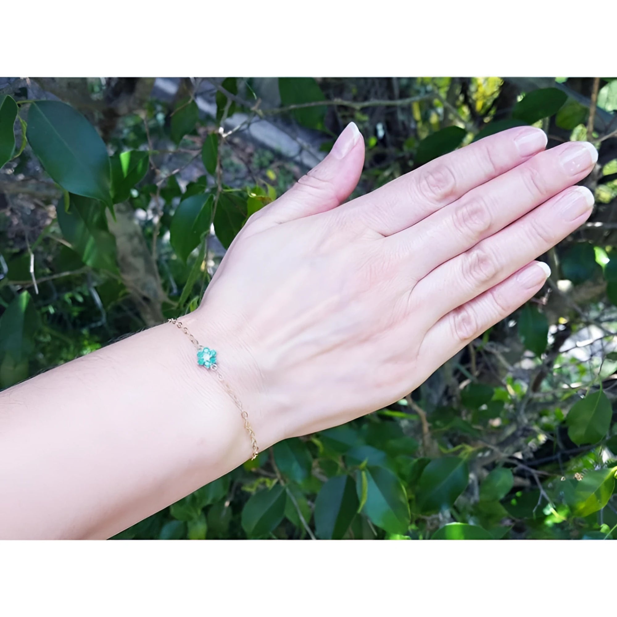 14K yellow gold bracelet with a central emerald and diamond cluster on a woman's wrist.