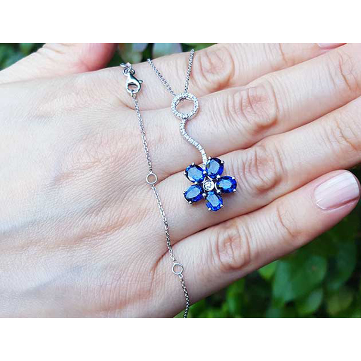 On a person&#39;s hand displaying a cluster of natural sapphires pendant white gold necklace white gold chain
