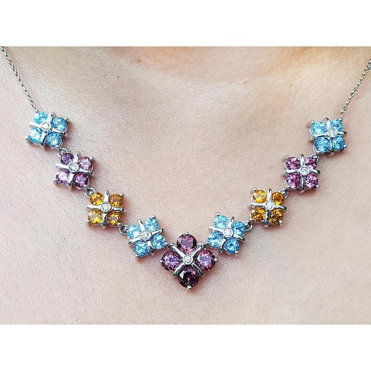 18K white gold necklace with tri-colored topaz X-cluster links and a central diamond.