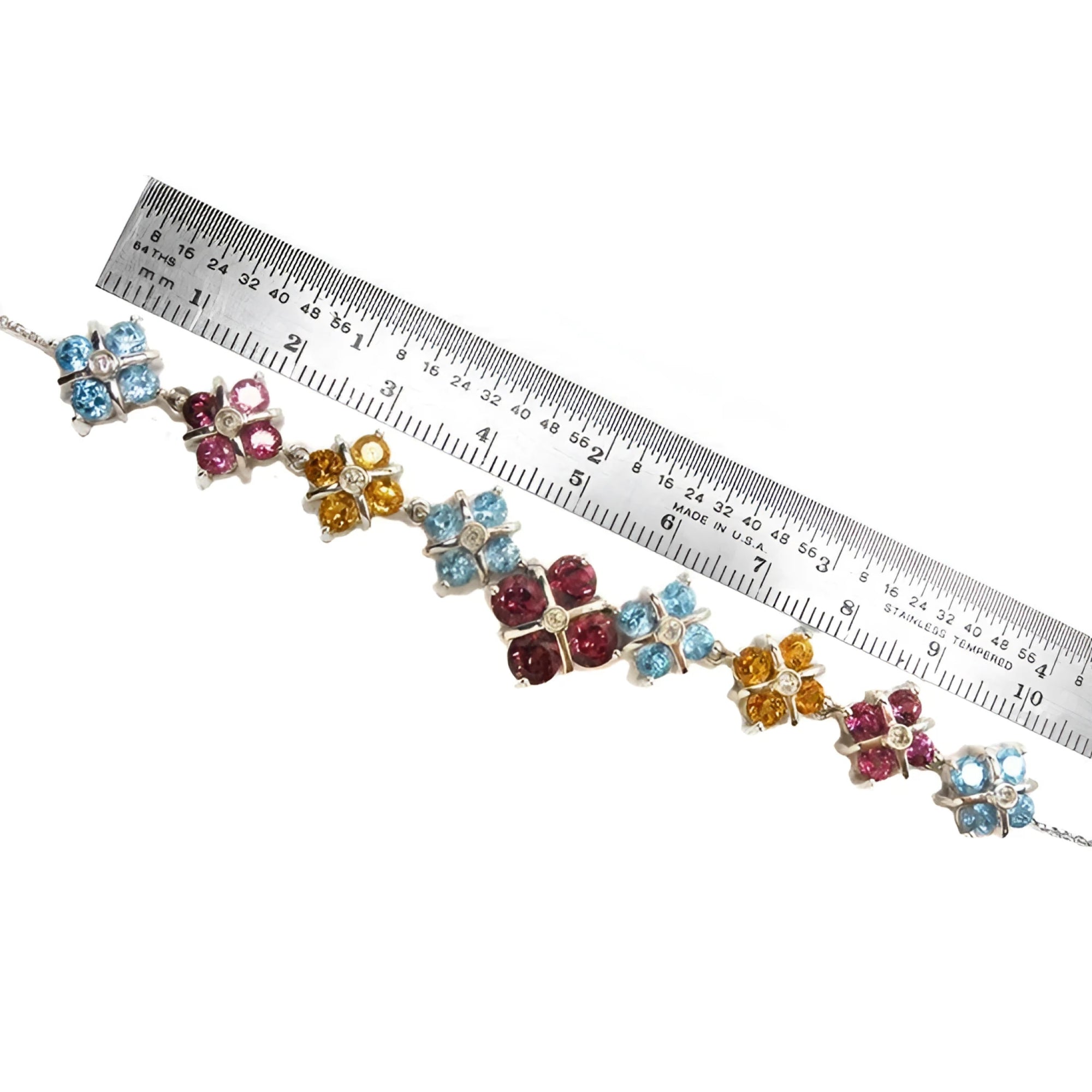 18K white gold necklace with X-cluster links, tri-colored topaz, and diamond, measured by a ruler.