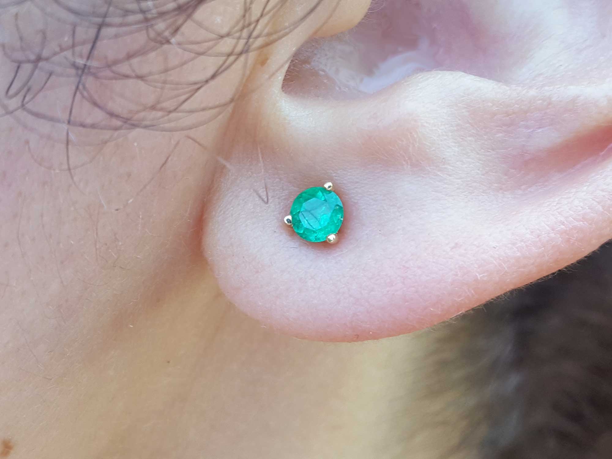 close-up of an earlobe with a Colombian emerald cocktail earring.