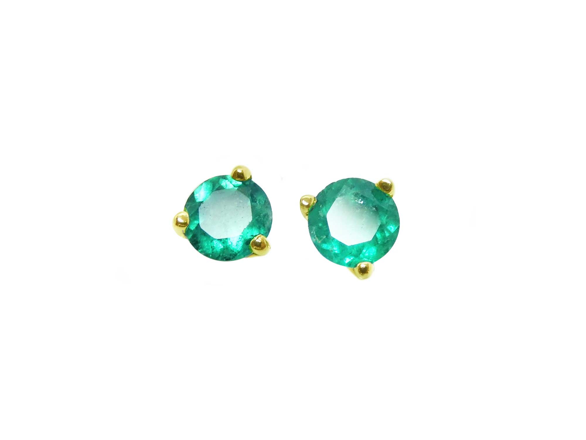 A pair of cocktail emerald stud earrings with a round cut design, set in 14K yellow gold.