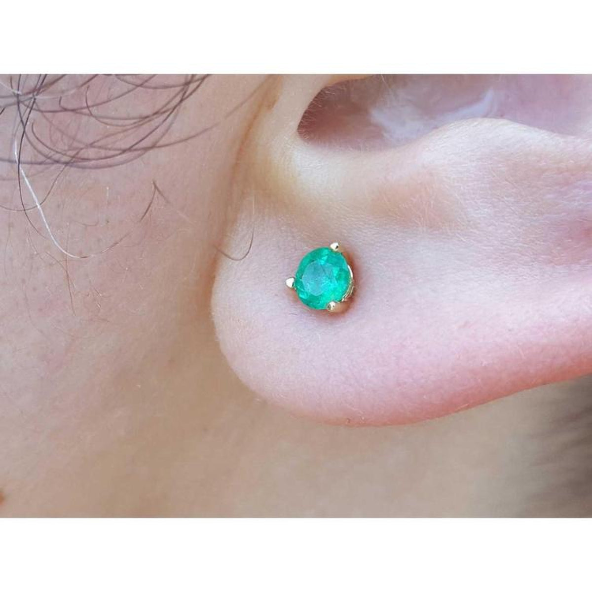 A cocktail emerald stud earring made of 14k yellow gold three prong set.