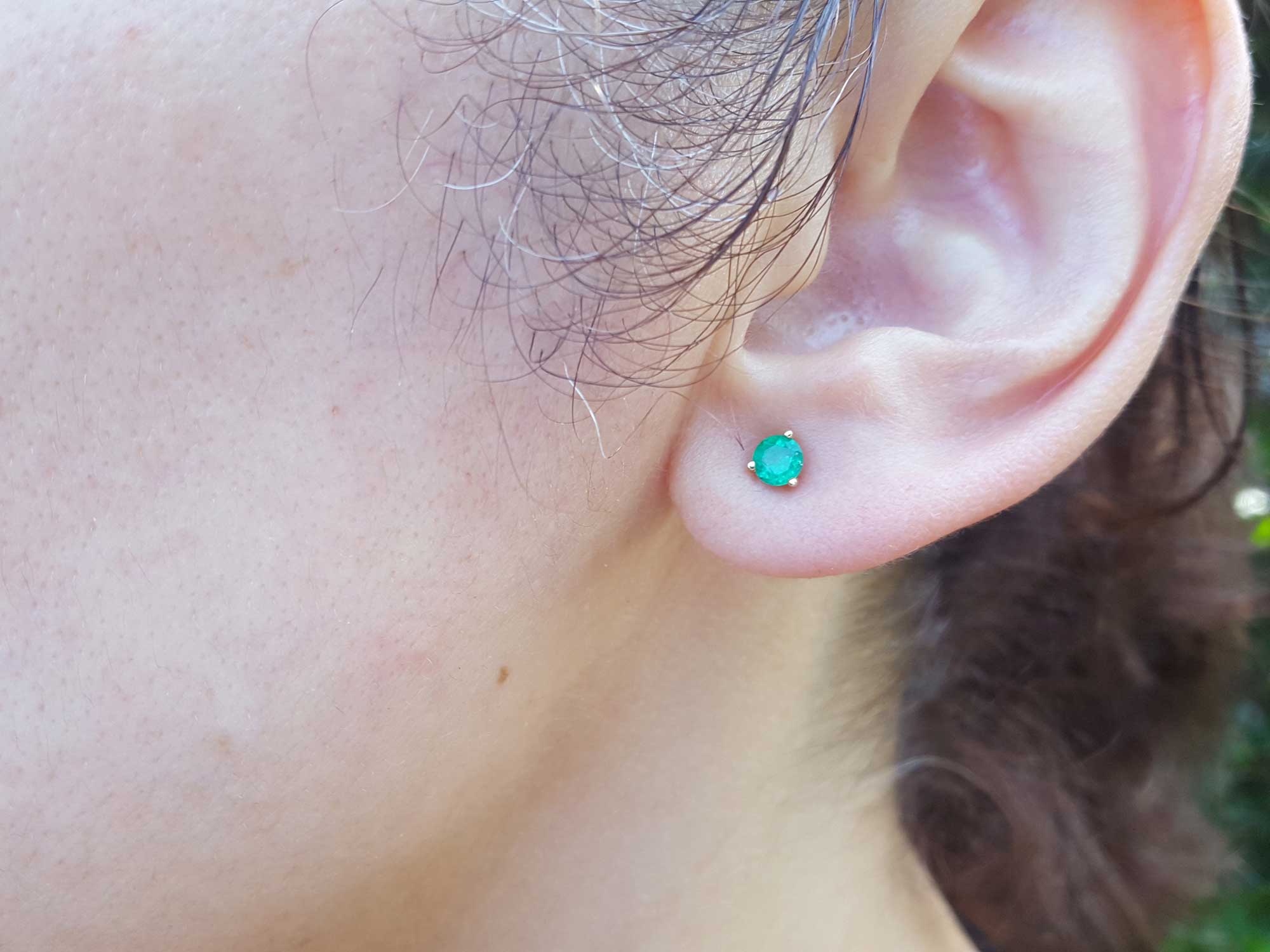 Close-up of a woman ear dressing a Colombian emerald cocktail earring.