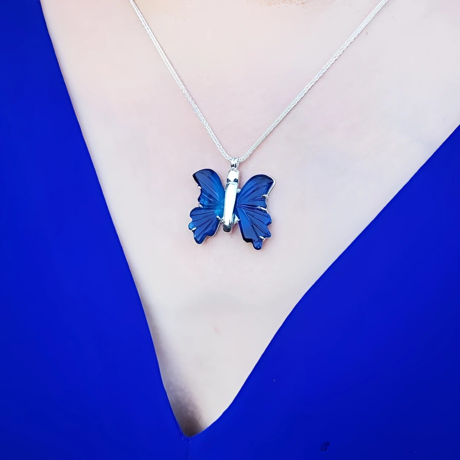 Dark blue natural agate butterfly pendant necklace with sterling silver chain on a woman's chest.