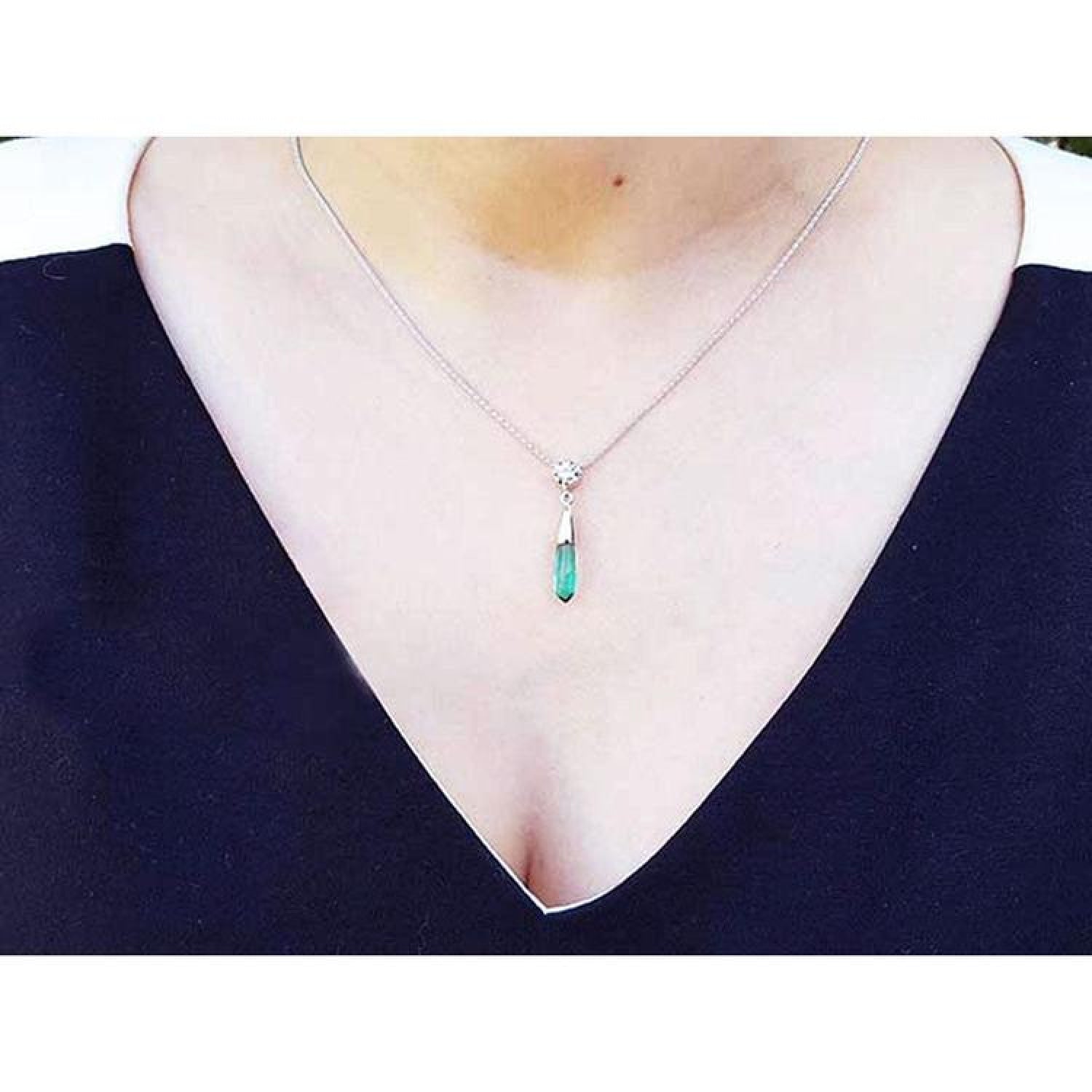 Colombian emerald briolette necklace with a diamond slider on a 14K white gold chain, worn on a woman's neck.