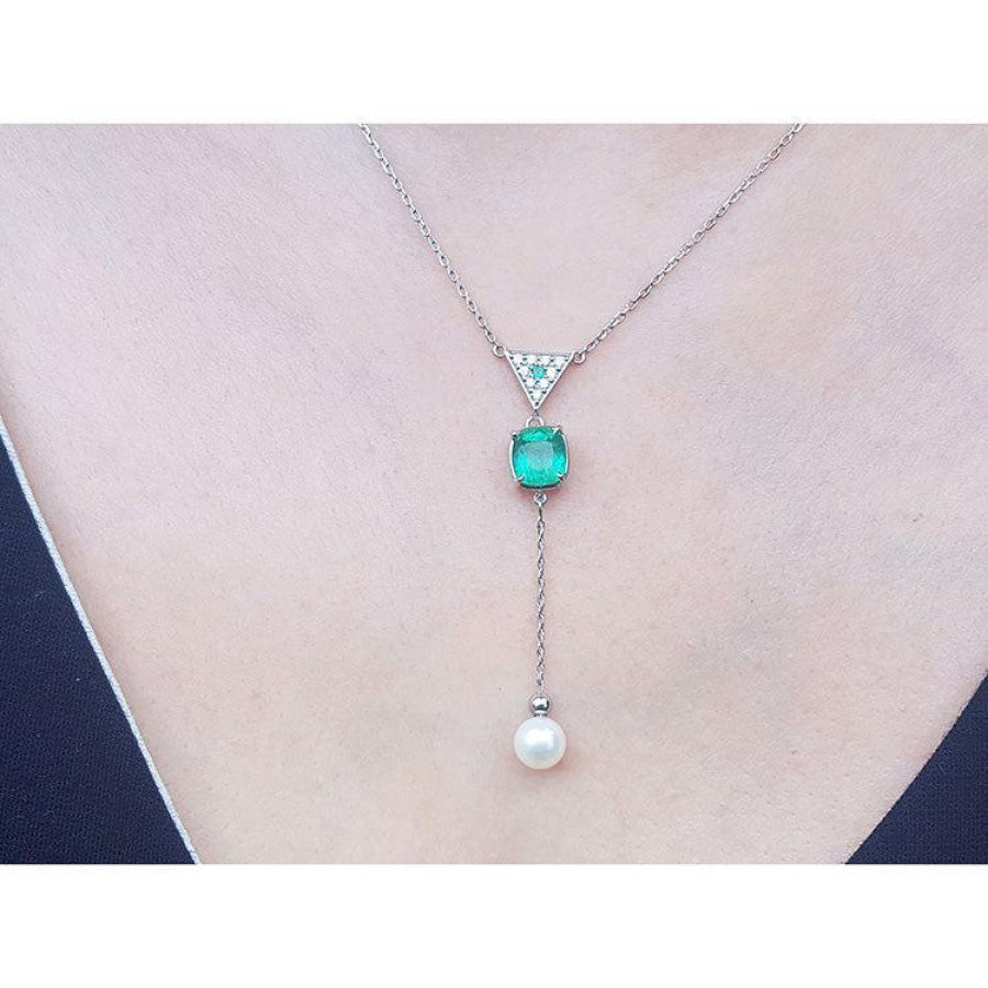 14K white gold necklace with triangle diamond cluster, cushion-cut emerald, and dangling white pearl.