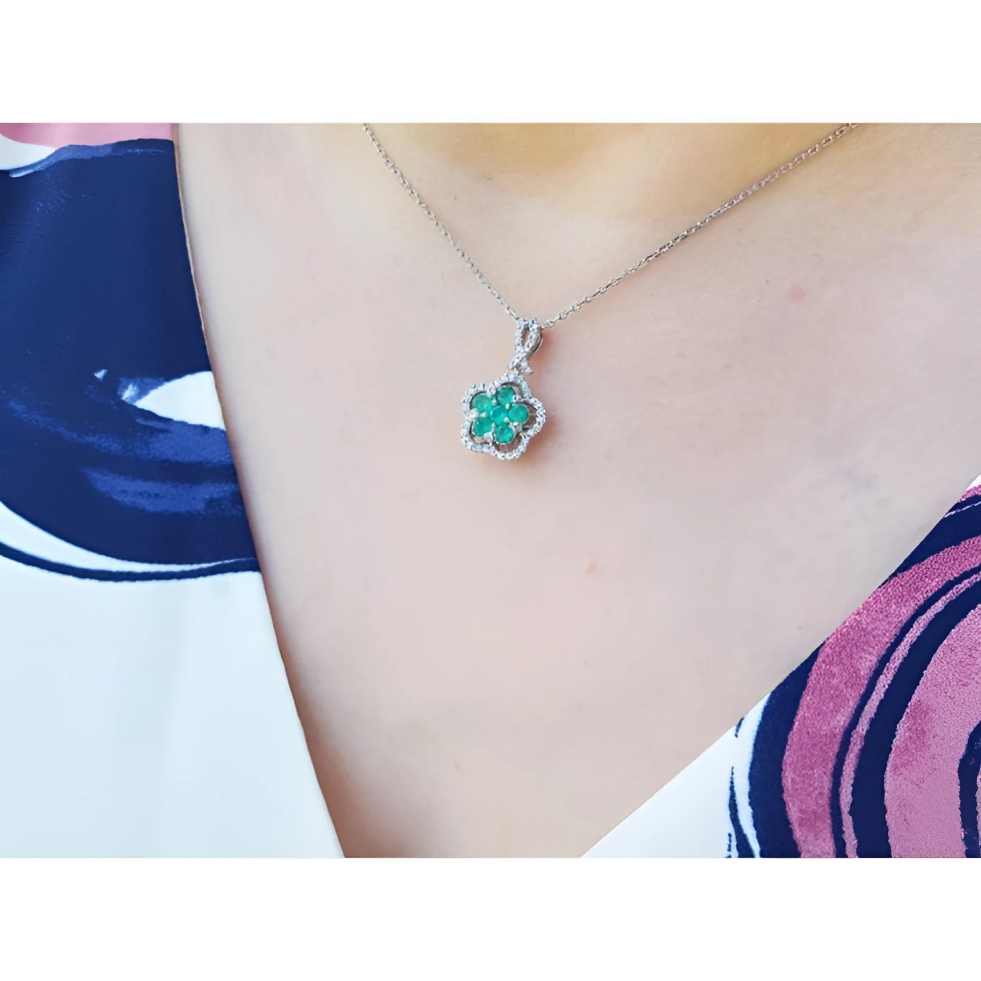 Emerald cluster necklace with diamonds in 14K white gold, clover-like design on a woman's neck.