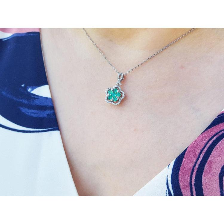 Emerald cluster necklace with diamonds in 14K white gold, clover-like design on a woman's neck.