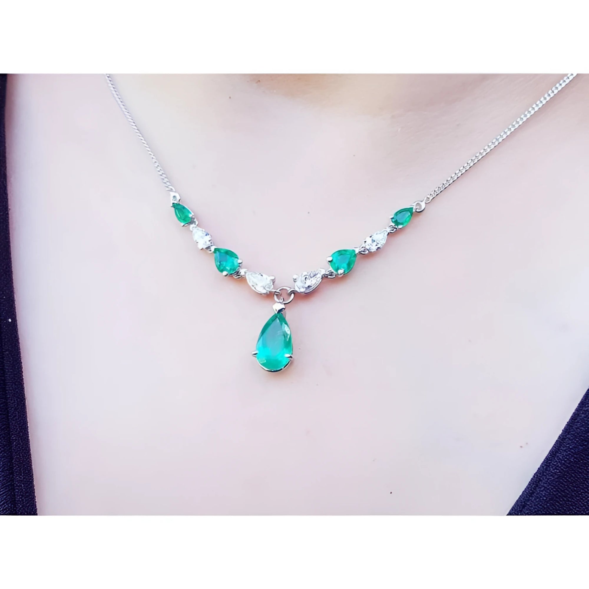 14k white gold necklace with pear-shaped emeralds and diamonds, featuring a large emerald drop.