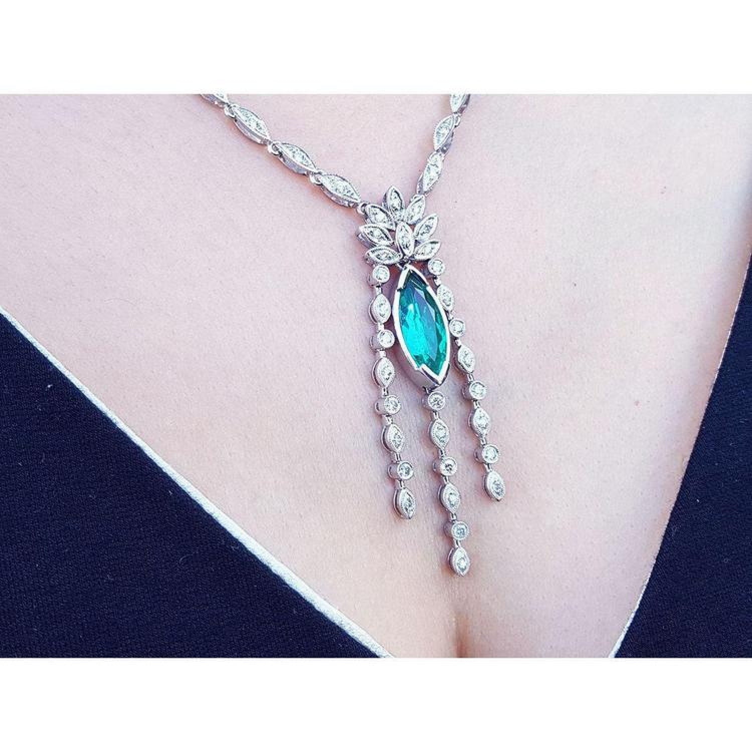 Marquise cut Colombian emerald necklace in 14K white gold with diamond links on a woman's chest.