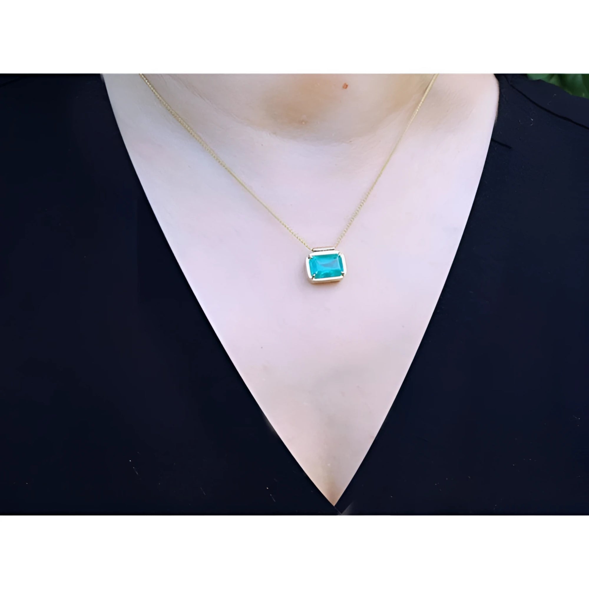 18K yellow gold necklace with a vibrant deep green emerald solitaire in an east-west setting.