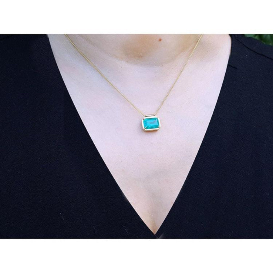 18K yellow gold necklace with a vibrant deep green emerald solitaire in an east-west setting.