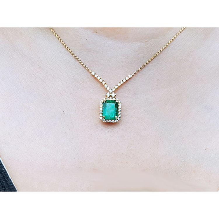 3.43 ct emerald halo necklace with natural diamonds on a 14K yellow gold chain.