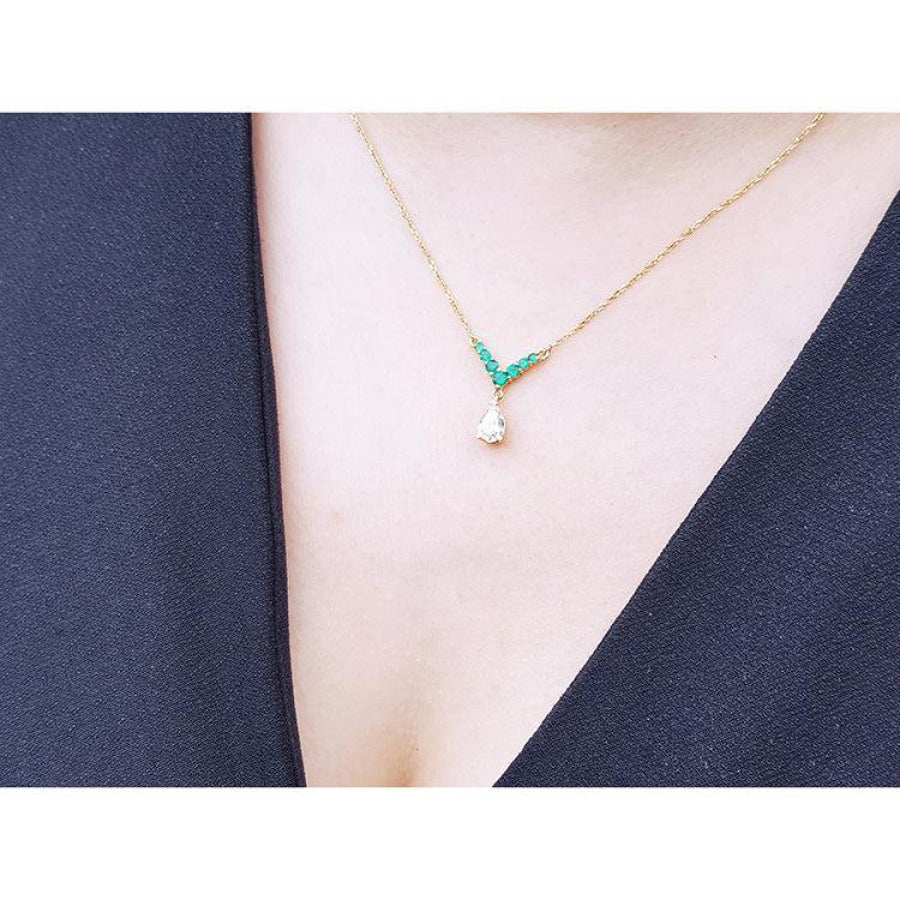14K gold necklace with pear-cut diamond and V-shaped emerald centerpiece on a model.