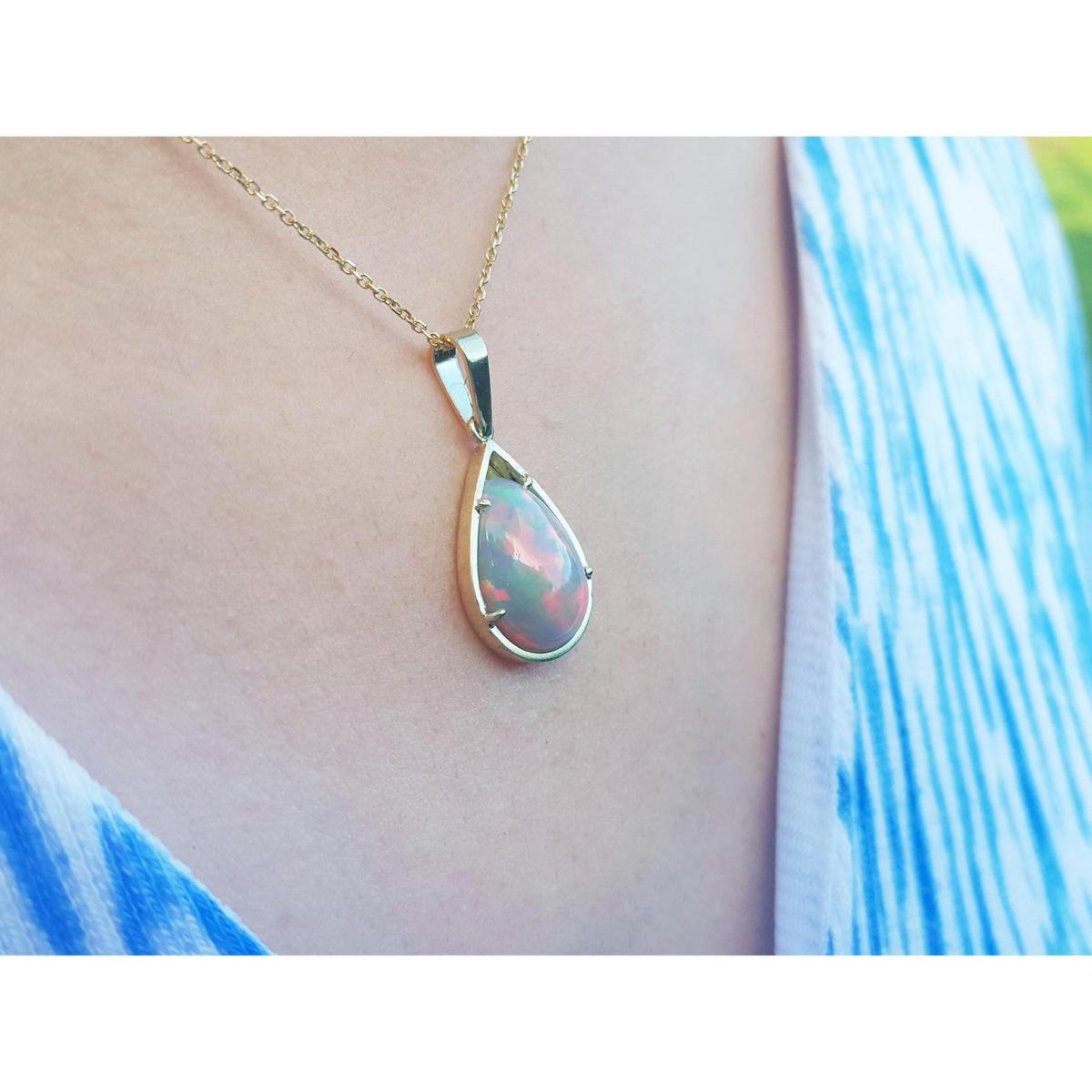 Opal pendant necklace on a person wearing a blue top
