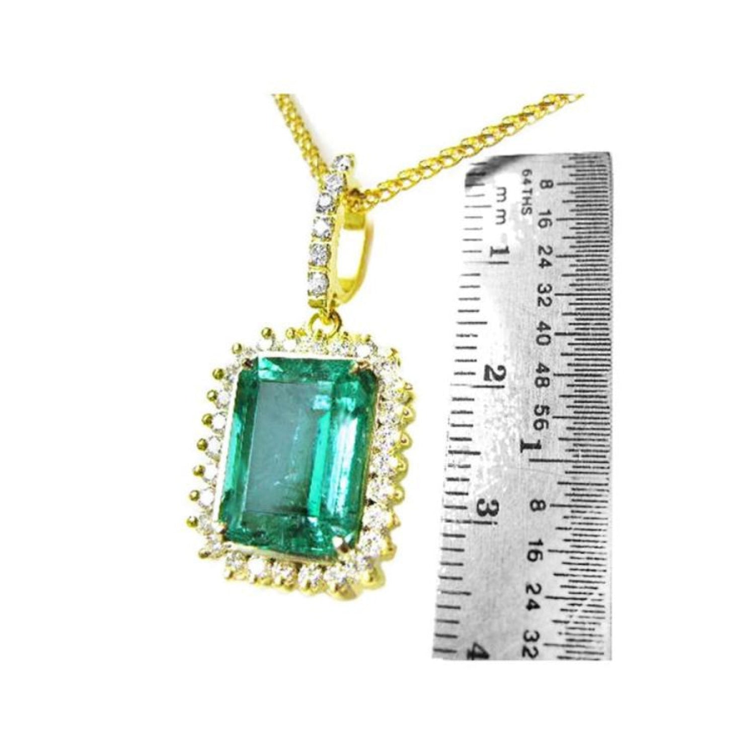 Emerald-cut emerald pendant with halo diamonds in 18K gold, shown next to a ruler for scale.