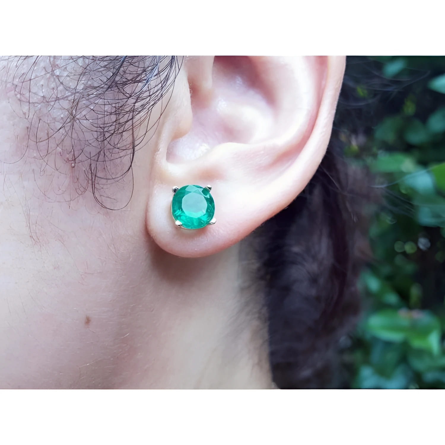 Round bluish-green Colombian emerald stud earring in 14K yellow gold, worn on an ear.