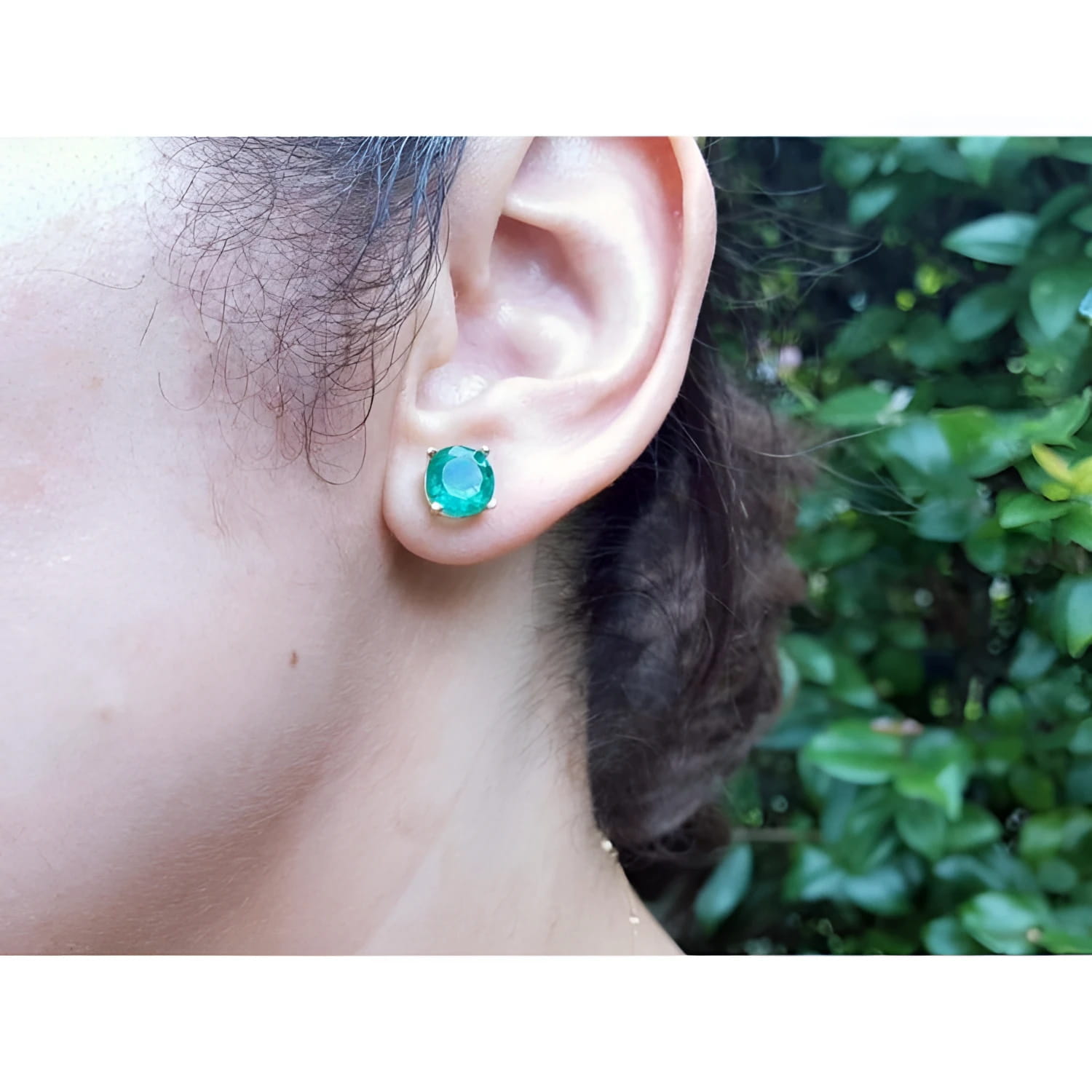 Colombian emerald stud earring, bluish-green round cut, in 14K yellow gold on an ear.